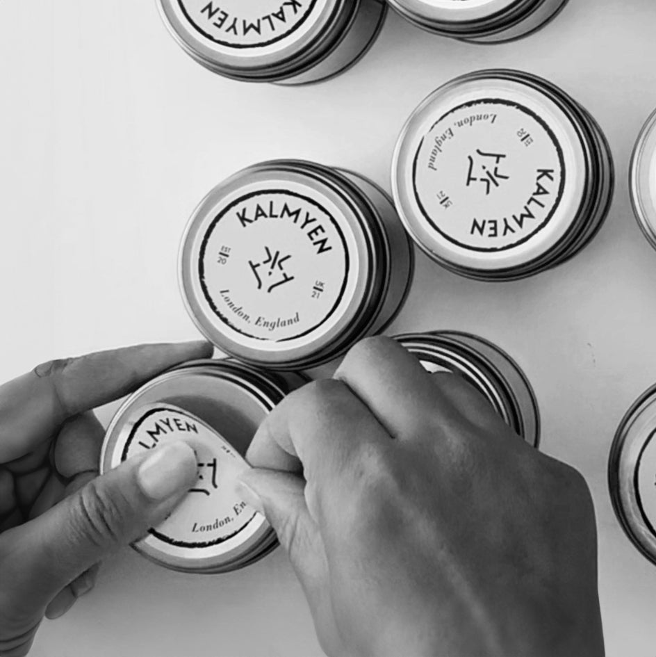 Kalmyen Keepsake tins being labelled, with a label being placed on the lid of the tin candle.