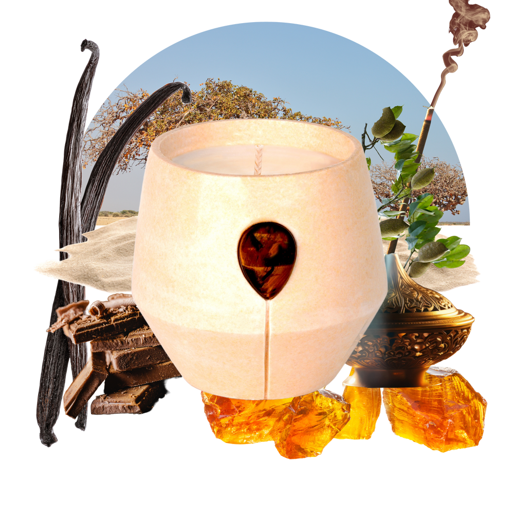 Image of Luna Amber Oro candle with its scent collage at the back - the text reads: Discover the fusion of Myrrh and Frankincense with Tigers Eye in our 24k gold-speckled vessel. This scent creates a rich, inviting aroma for a positive, confidence-boosting, well-balanced space.