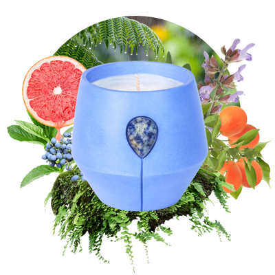 Image of Luna Petrichor candle with its scent collage at the back - the text reads: Embark on a journey with Spearmint, Cedarwood, the soothing energy of Blue Spot Jasper in our calming blue vessel. Evoking the deep forest, this invigorating scent is designed to uplift your space