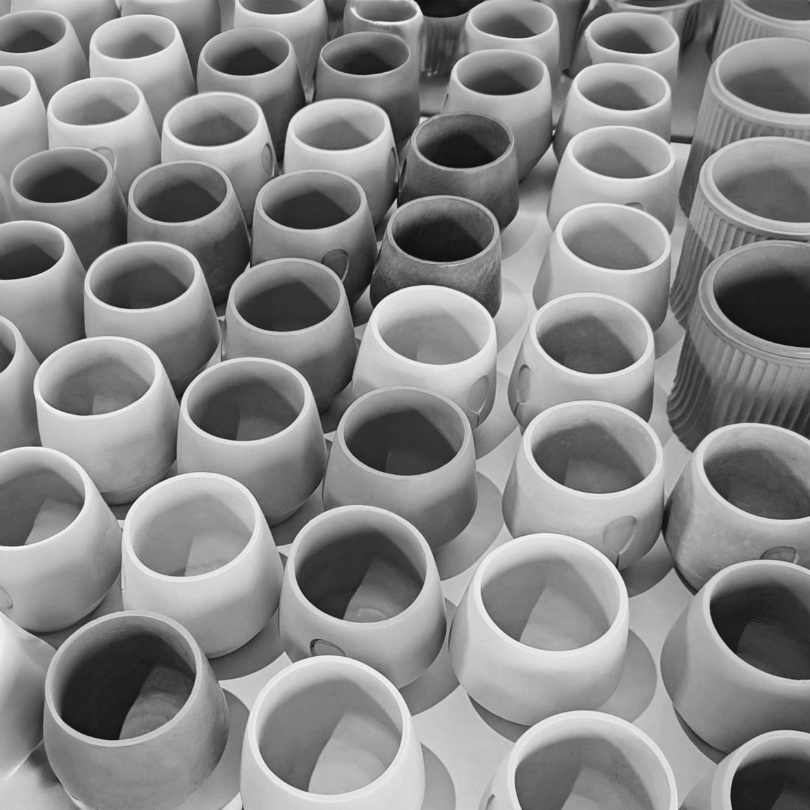 Rows of Kalmyen Luna jars in black and white on a production table, awaiting finishing touches and gemstone adornments.